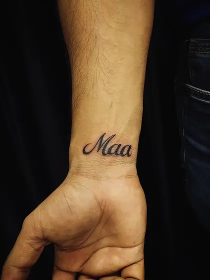 A classic 'Maa' (Mother) tattoo on the wrist. We use clean, elegant script to create a timeless tribute to a mother's love.