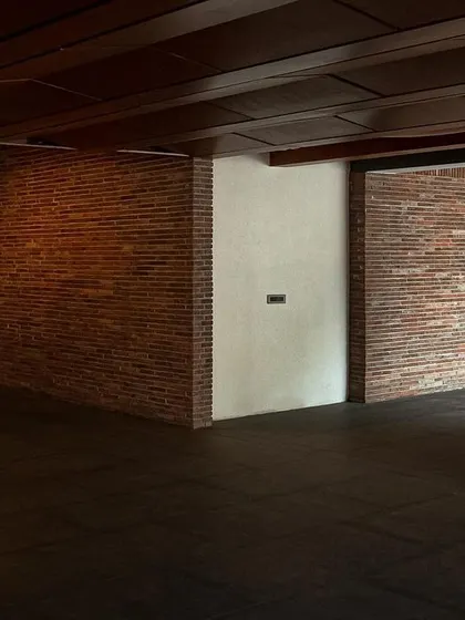 The interior of Samavana features exposed brick walls and a dark wood-paneled ceiling. This combination of honest, tactile materials creates a warm and atmospheric space, enhanced by carefully placed accent lighting.