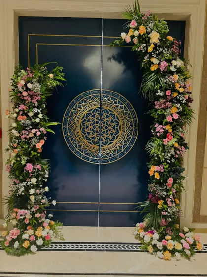 This stunning floral entrance arch was designed for an engagement party. The asymmetrical arrangement of colorful flowers against the ornate blue door creates a grand and welcoming statement.