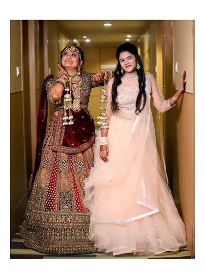 A fun and playful moment between the bride and her bridesmaid. Their poses and expressions show the lighthearted joy and strong friendship they share.