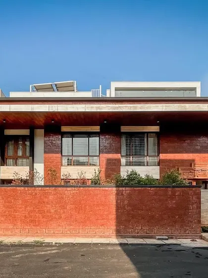 A frontal view of the Hennur residence, highlighting the use of a low brick wall for privacy while maintaining a connection to the streetscape.