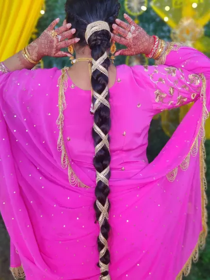 A Lohri special hairstyle featuring a long, neat braid intricately woven with golden lace and a traditional parandi.