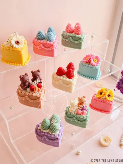 My full assortment of nine unique birthday cake candles, displayed on a clear stand. There's a design for everyone, from teddy bears and strawberries to beautiful floral toppings.