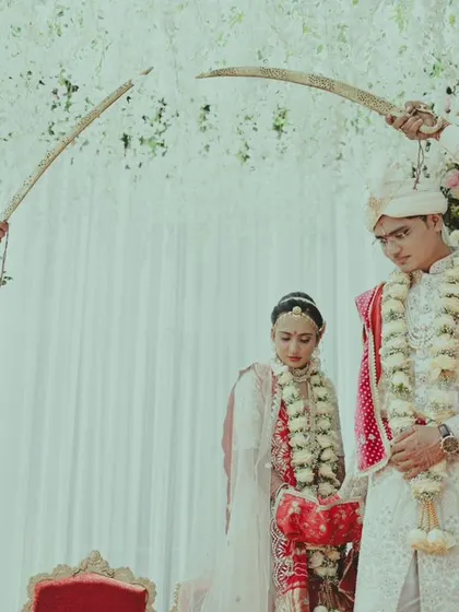 A traditional Rajput wedding moment, with family members holding swords over the couple in a gesture of honor and protection.