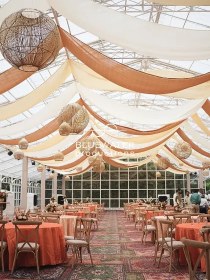The dining hall ceiling is draped with flowing fabrics in shades of cream and terracotta, with woven lampshades hanging above.