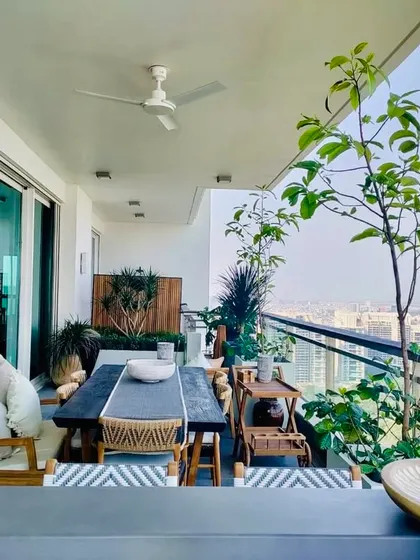 A well planned garden is a room outside your home. This balcony is a perfect combination of aesthetics, greenery, and utility, with a large dining table, comfortable chairs, and a variety of potted plants.