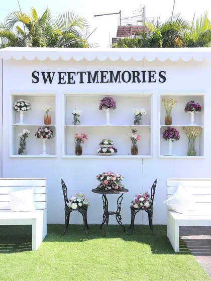 A 'Sweet Memories' photo spot with a clean, white shelving unit and Parisian-style cafe seating, perfect for capturing elegant moments.