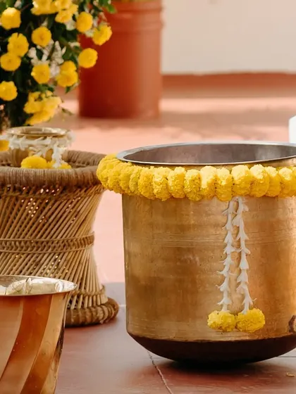 A close-up of the traditional brass vessels and wicker stools used in our Haldi ceremony setups.