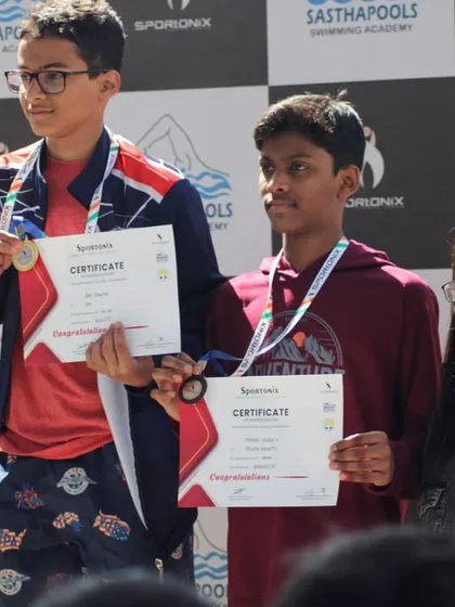 Young male swimmers proudly display their medals and certificates on the victory stand.
