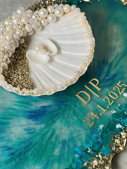A detailed shot of the seashell ring holder, adorned with pearls and set on a beautiful teal and gold resin tray.