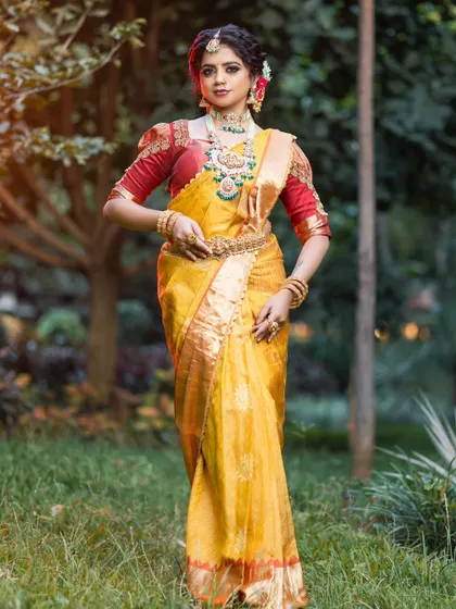 A full-length shot showing the beautiful drape of the yellow silk saree and the rich contrast of the red embroidered blouse.