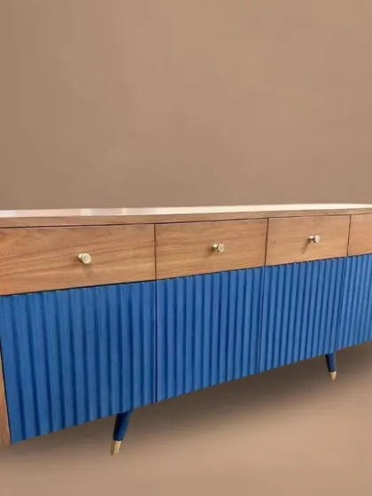 A wide media console featuring a natural wood top and a vibrant blue fluted base. This piece is a perfect example of our custom color and material combination capabilities.
