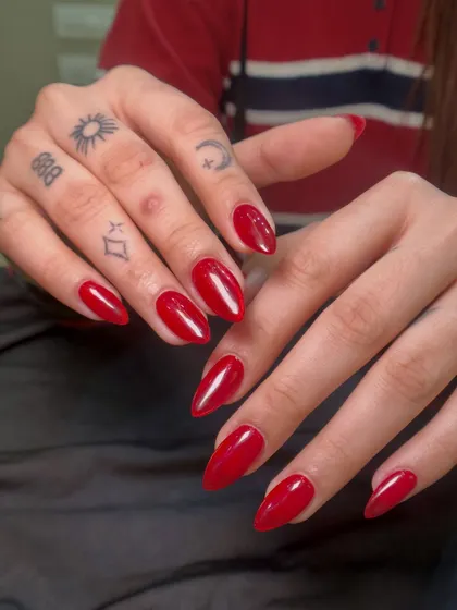 This client's hand tattoos pair so well with the bold, classic red manicure. The glossy finish makes the color look rich and luxurious.