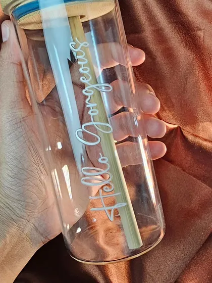 A closer look at the custom glass tumbler with a bamboo lid and straw. The clear glass is perfect for showcasing iced coffees and other colorful drinks.