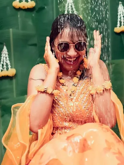 The pure joy of a Haldi ceremony, captured as the bride laughs while being showered with water.