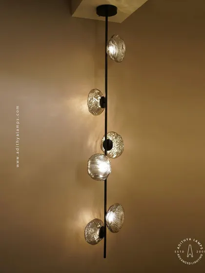 This vertical fixture features textured, moon-like chrome orbs attached to a central black rod. It's a striking, artistic piece that works well in corners or narrow spaces, adding a touch of celestial-inspired modernism.