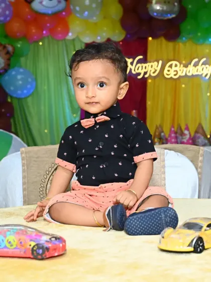 A candid shot of the birthday boy, Derick, sitting at a table with his new toys in front of his jungle-themed birthday backdrop.