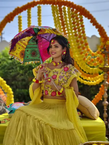 A vibrant and traditional setup for a haldi ceremony. The circular marigold arch and the bride-to-be in her floral jewelry create a picture-perfect moment, captured beautifully.