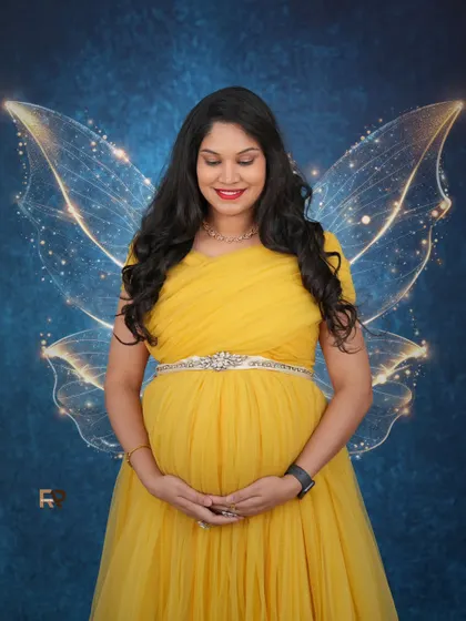 A moment of quiet reflection. This mom-to-be looks absolutely radiant in a yellow tulle gown, complemented by fantasy wings against a deep blue, starry backdrop. We can customize backdrops and effects to match your vision.