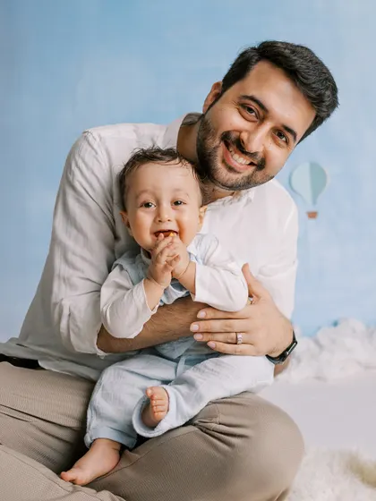 A father holding his happy baby. The simple, clean background keeps the focus on their joyful interaction.