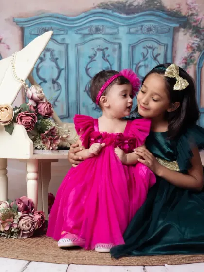 Sisterly love shines in this photo, with the older sister admiring the younger one at our miniature piano.
