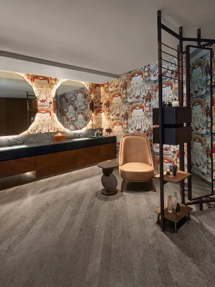 This bathroom at the Baid Residence features wallpaper by Cole & Sons with a rich, historical pattern. The texture of the wallpaper is paired with the smooth, veined marble of the vanity and the herringbone pattern of the wood floor.