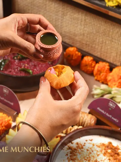 A guest enjoying a mini pani puri from our Indian grazing table. We present classic street food favorites in an elegant, bite-sized format, perfect for a sophisticated party setting.