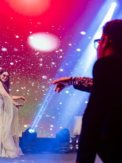A dramatic and artistic shot of a sangeet performance. The lighting and composition highlight the storytelling aspect of the dance.