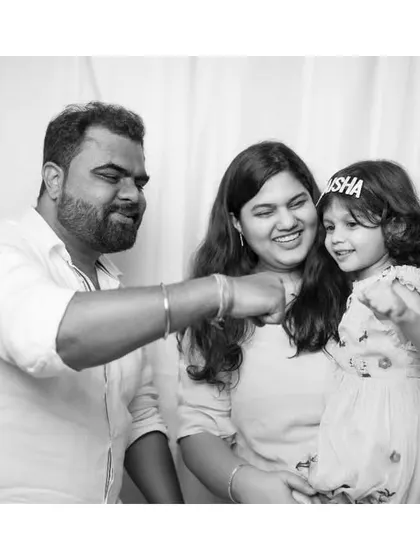 A black and white photo showing a candid, interactive moment between a father, mother, and their daughter. It's the small, happy interactions that make the best memories.