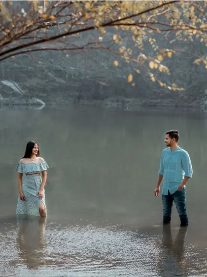 A creative and serene shot of a couple standing in the water, reflecting their calm and steady love for each other amidst a beautiful landscape.