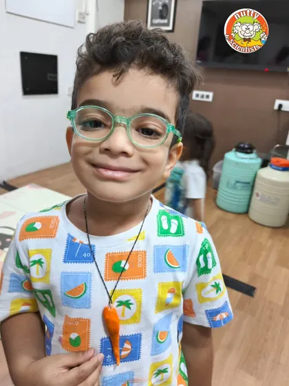 Another proud creator with his finished dino-tooth necklace. The bright orange tooth is ready to be worn, a trophy from his Jurassic adventure.