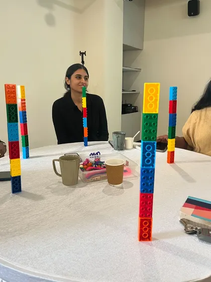 An educator smiles as she participates in a tower-building activity. The joy and engagement seen here are what I strive to help teachers replicate in their own learning environments.