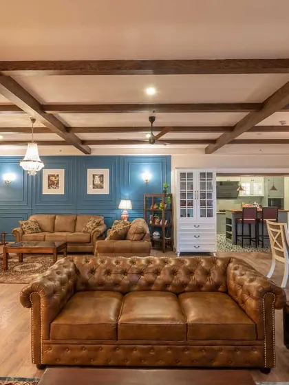 We love blending styles to create unique spaces. This living room combines the warmth of industrial design with classic Victorian elegance, featuring exposed wooden ceiling beams, a chesterfield sofa, and a striking blue accent wall for a truly memorable interior.