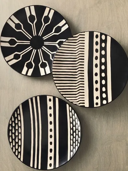 A set of three modern, black and white geometric plates, perfect for a contemporary wall art display.