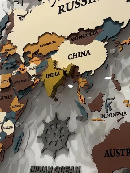 A close-up of the Asia and Australia section of the world map, showing the engraved country names and the nautical-themed icons surrounding the map.