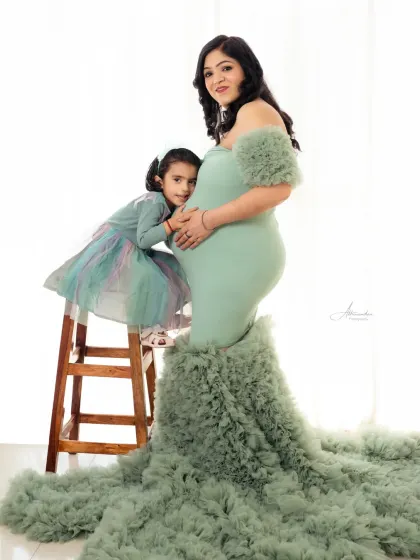 A beautiful portrait of an expecting mother in a stunning green gown, with her daughter giving the baby bump a hug.