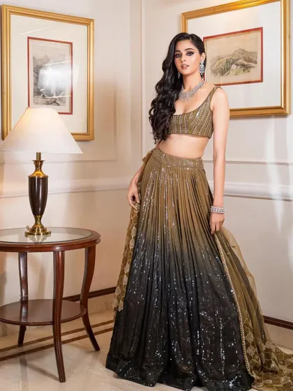 A glamorous reception look with an olive and black ombre lehenga. The makeup is kept sophisticated with a classic smokey eye and voluminous hair.