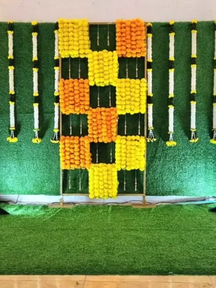 A traditional backdrop setup with a marigold checkerboard pattern on a grass wall, ready for seating to be added.