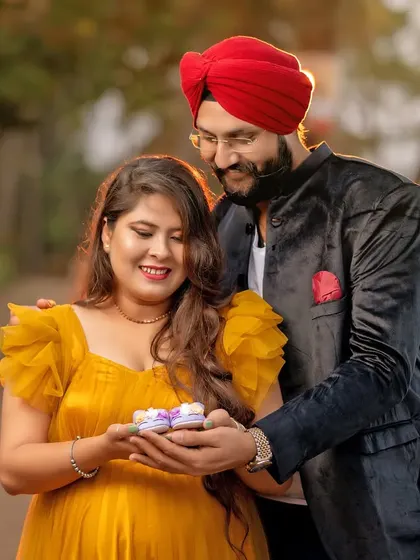 An outdoor maternity shot capturing a sweet moment between a couple. They are looking at tiny baby shoes, symbolizing their anticipation and excitement for their new arrival.
