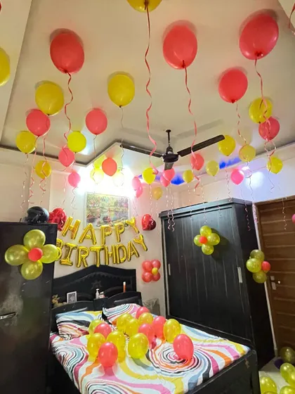 Sometimes, the best surprises are the simple ones. I filled this bedroom with red and yellow balloons, both on the ceiling and the bed, and added a "Happy Birthday" foil balloon banner to create a joyful and instant party atmosphere.