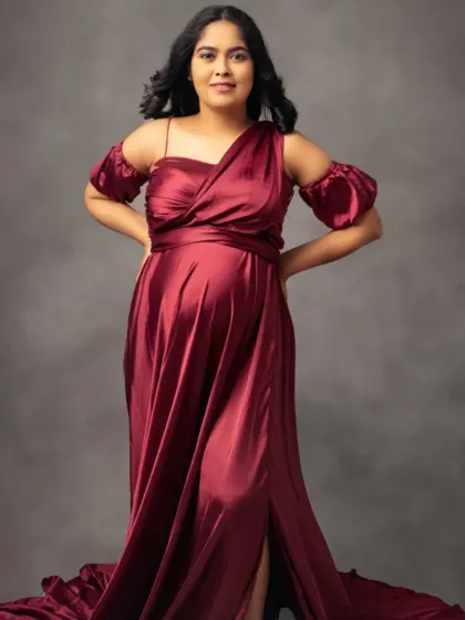 A full-length view of our beautiful burgundy satin gown, showcasing its flowing train and elegant off-the-shoulder design.