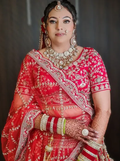A gorgeous bride ready for her big day. This image captures the complete look, from the intricate hairstyle to the stunning red lehenga and heavy jewelry.