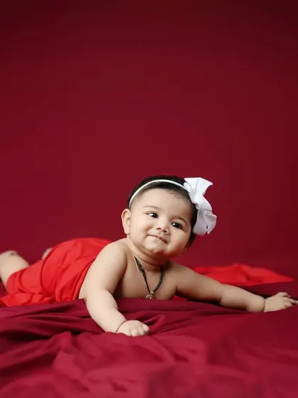 Another beautiful portrait using a simple, bold red backdrop to highlight the baby's sweet smile and playful pose.