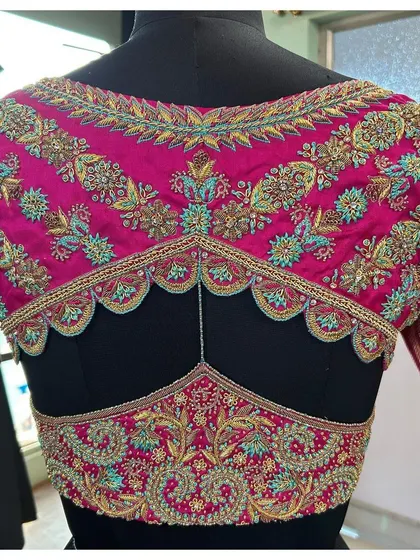 This pink blouse features a unique double-panel back design with scalloped edges. The intricate floral and peacock embroidery makes it a standout piece for any celebration.