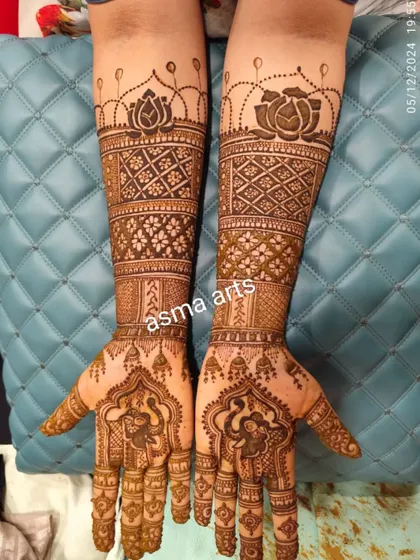 A beautiful symmetrical design featuring lotus flowers at the top and intricate jaali (net) patterns on the forearms. The palms have a classic mandala-style design.