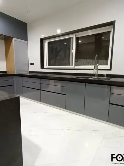 This wide shot showcases the expansive counter space in a U-shaped kitchen. The handleless grey cabinets and white marble-style floor create a clean, modern, and spacious environment.