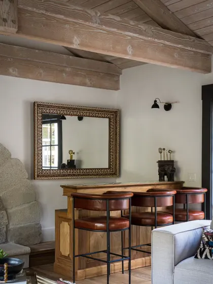 A close-up of the bar area in the Saratoga living room, nestled next to the stone fireplace. The warm wood and leather create an inviting, club-like feel.