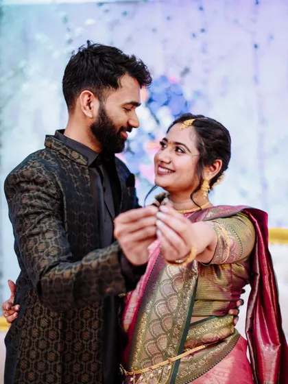 A romantic shot of an engaged couple looking at each other while holding their rings.
