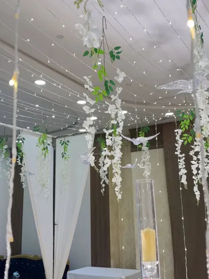 A detail shot of the ceiling decor for the Nikah setup. Hanging wisteria, green vines, and decorative birds create a whimsical, garden-like feel indoors.