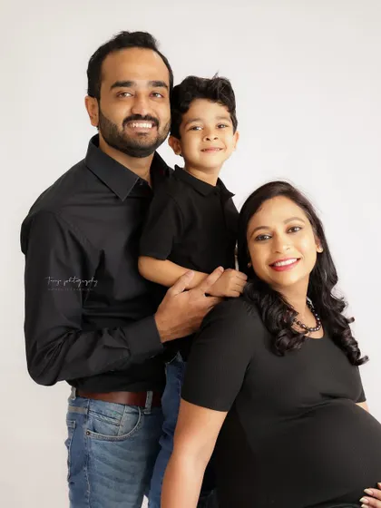 A happy and classic family portrait. This shot beautifully captures the excitement of a growing family, with everyone dressed in coordinating black outfits.